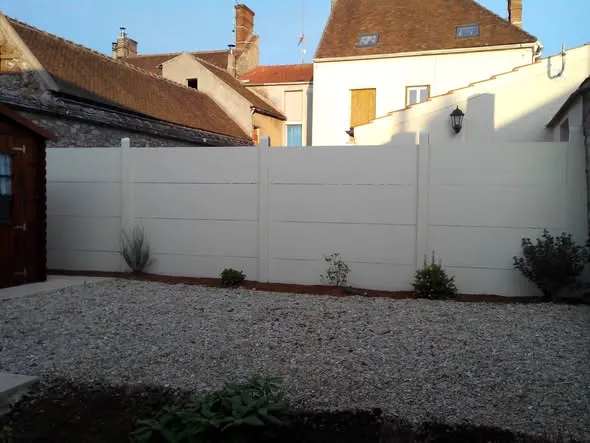 Mur de clôture en plaques béton peint en blanc cassé