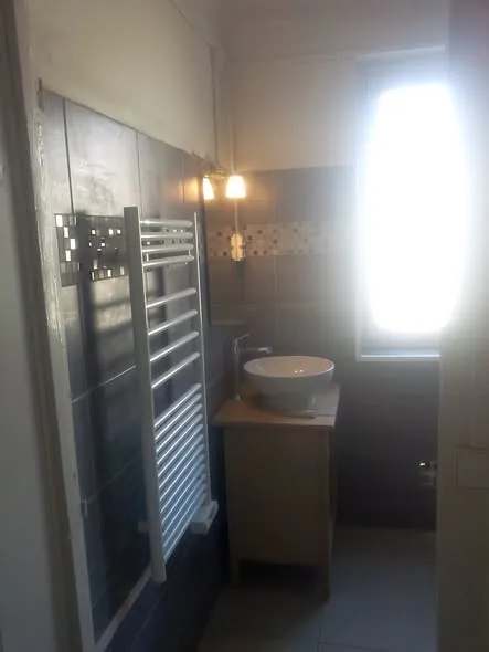 Salle de bain rénovée avec faïence grise, meuble vasque et sèche-serviettes